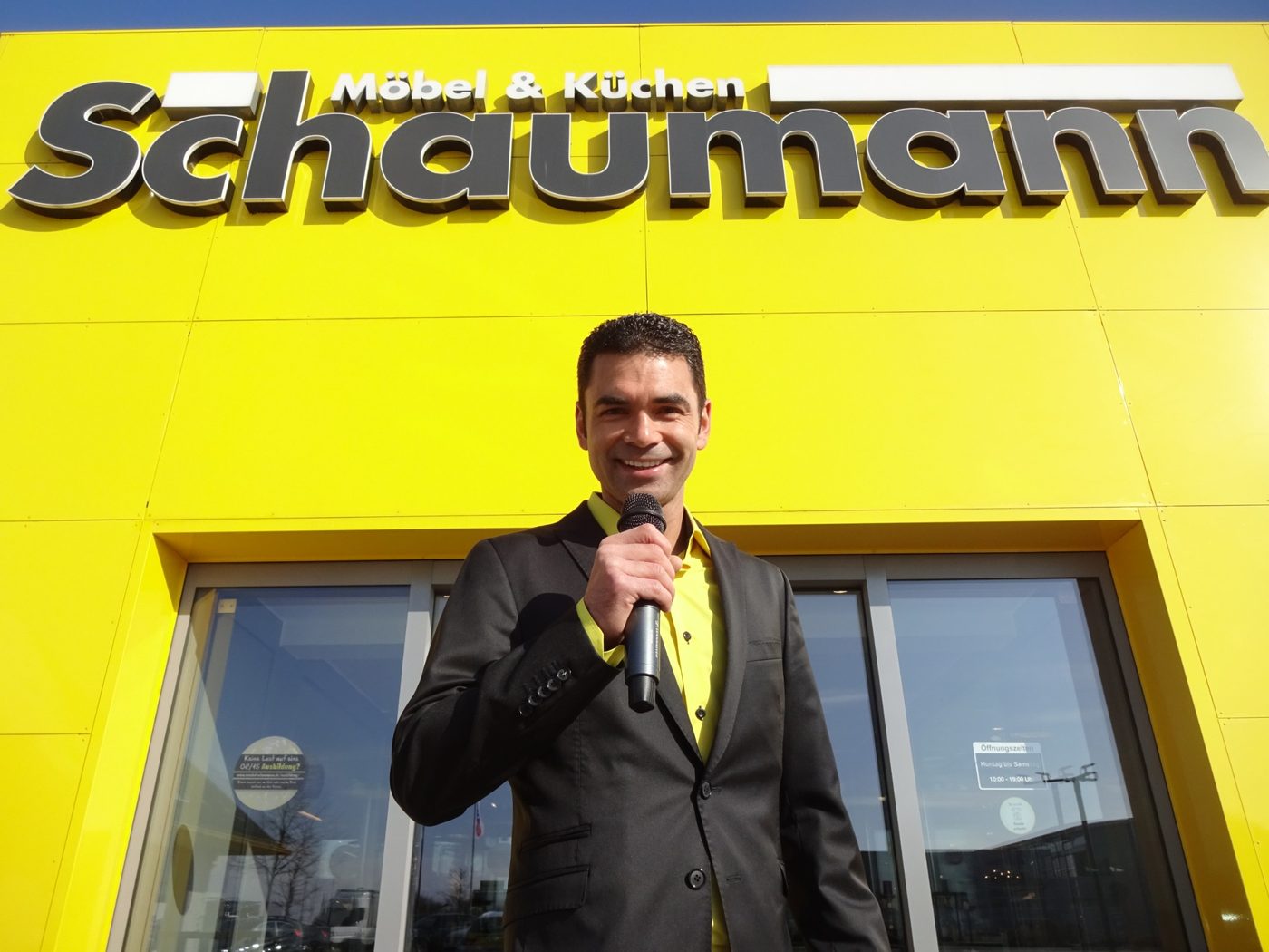 Verkaufsmoderator Peter Juhle vor Möbel Schaumann mit Mikrofon